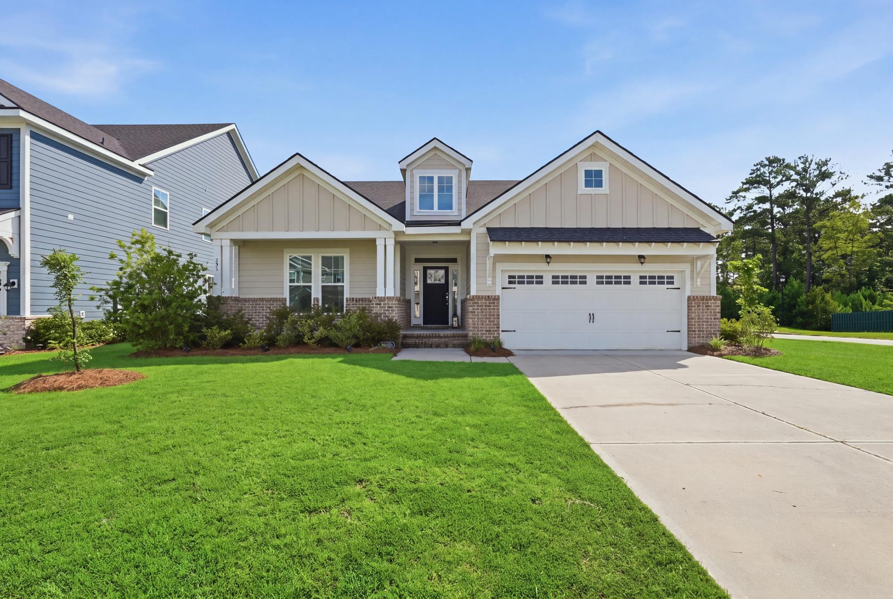 Front of a single-story home with a two-car garage and a green lawn on a sunny day